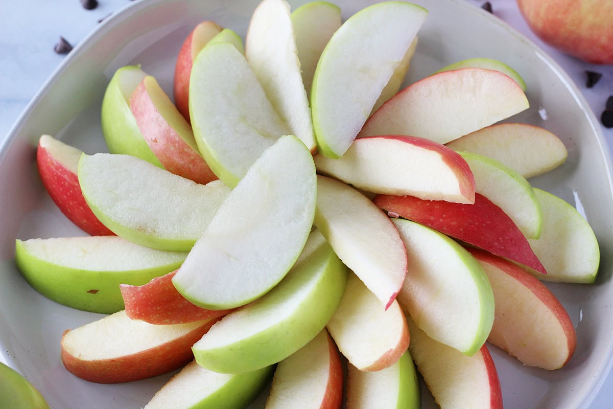 Granny smith and Fuji apple slices layered on a white plate.