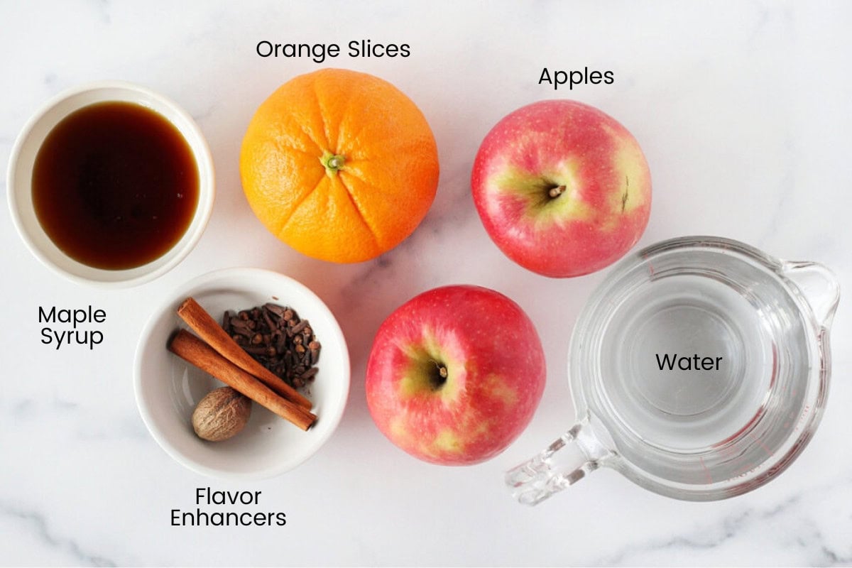 Apples, an orange, maple syrup and spices for homemade apple cider.