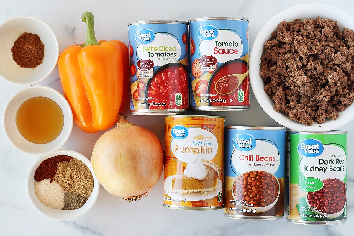 Cans and bowls of ingredients on a white marble countertop for healthy pumpkin chili.