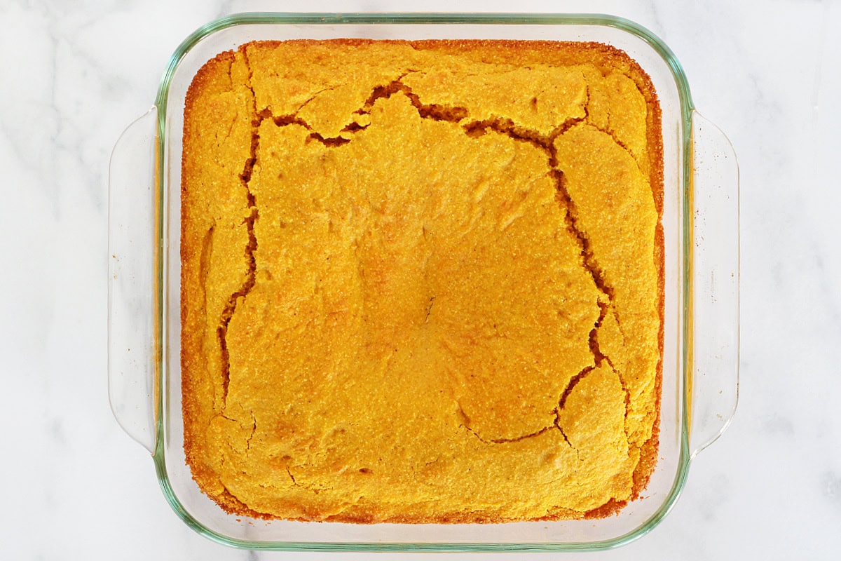 Overhead photo of baked healthy pumpkin cornbread in a glass pan.