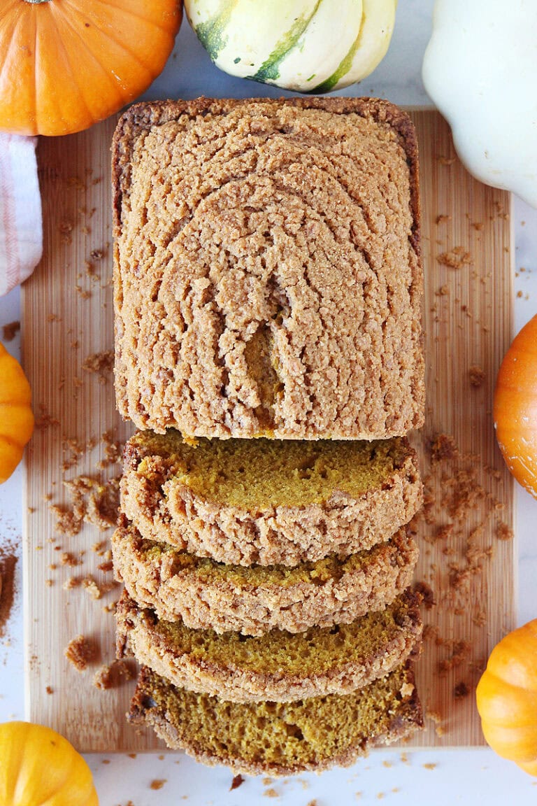 Overhead photo of pumpkin bread on a cutting board surrounded by pumpkins.