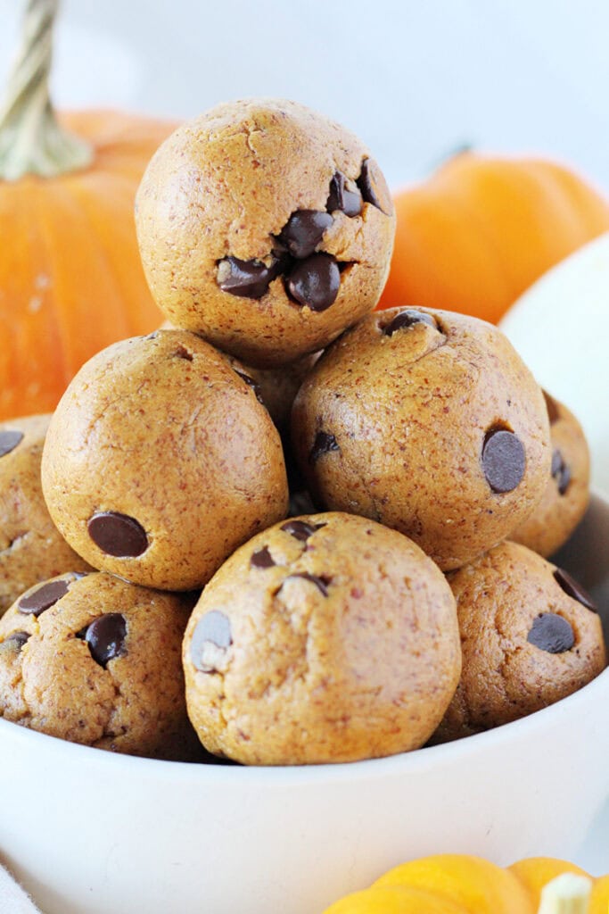 A stack of fall protein bites with dark chocolate chips in a white bowl.