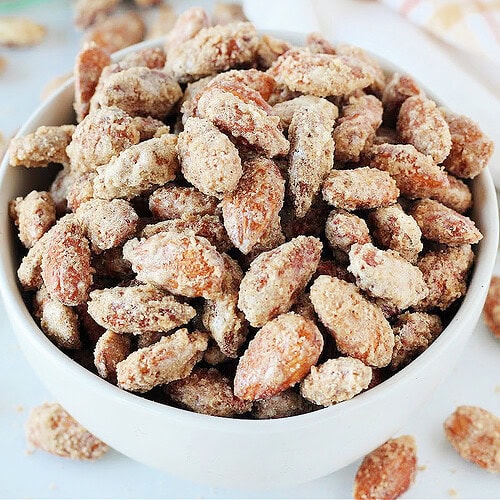 Up close photo of homemade candied almonds in a white bowl.