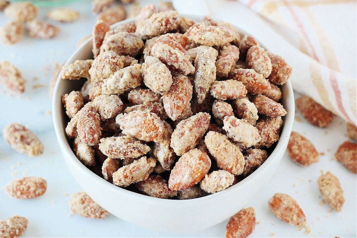 Up close photo of homemade candied almonds in a white bowl.