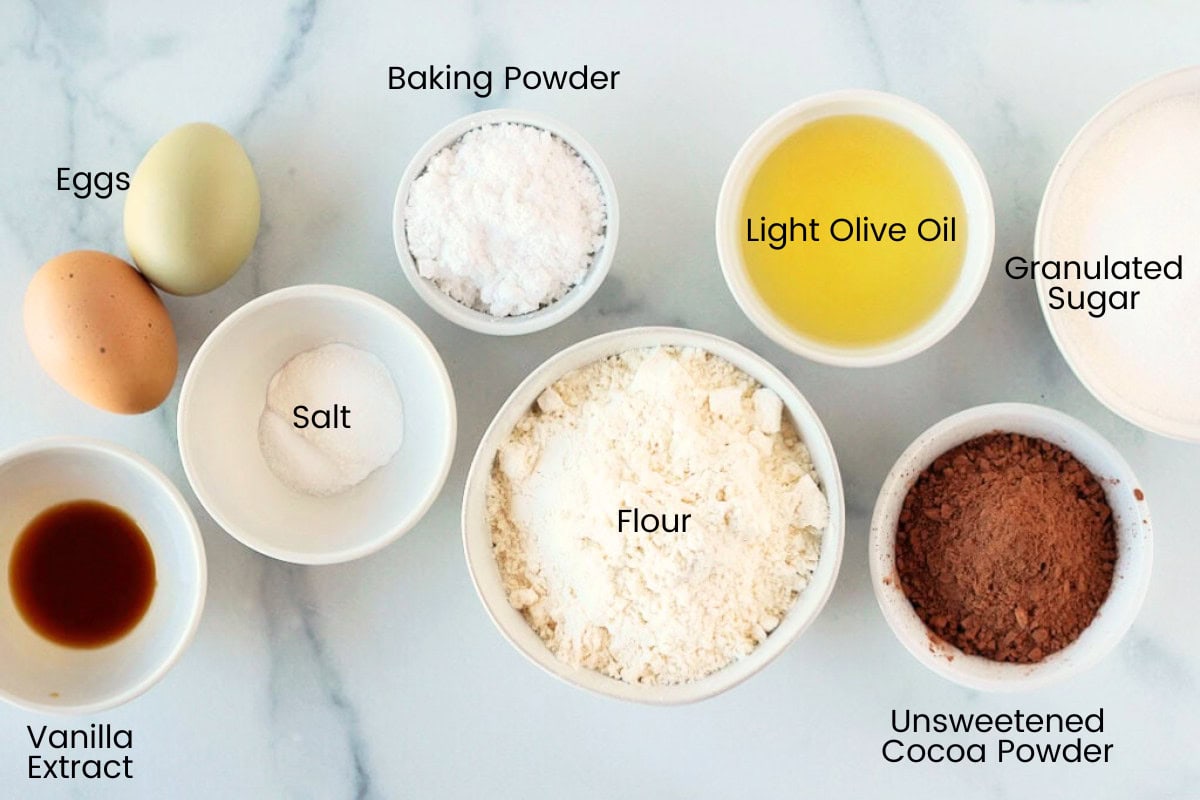 Labeled ingredients for chocolate crinkle cookies on a white marble countertop.