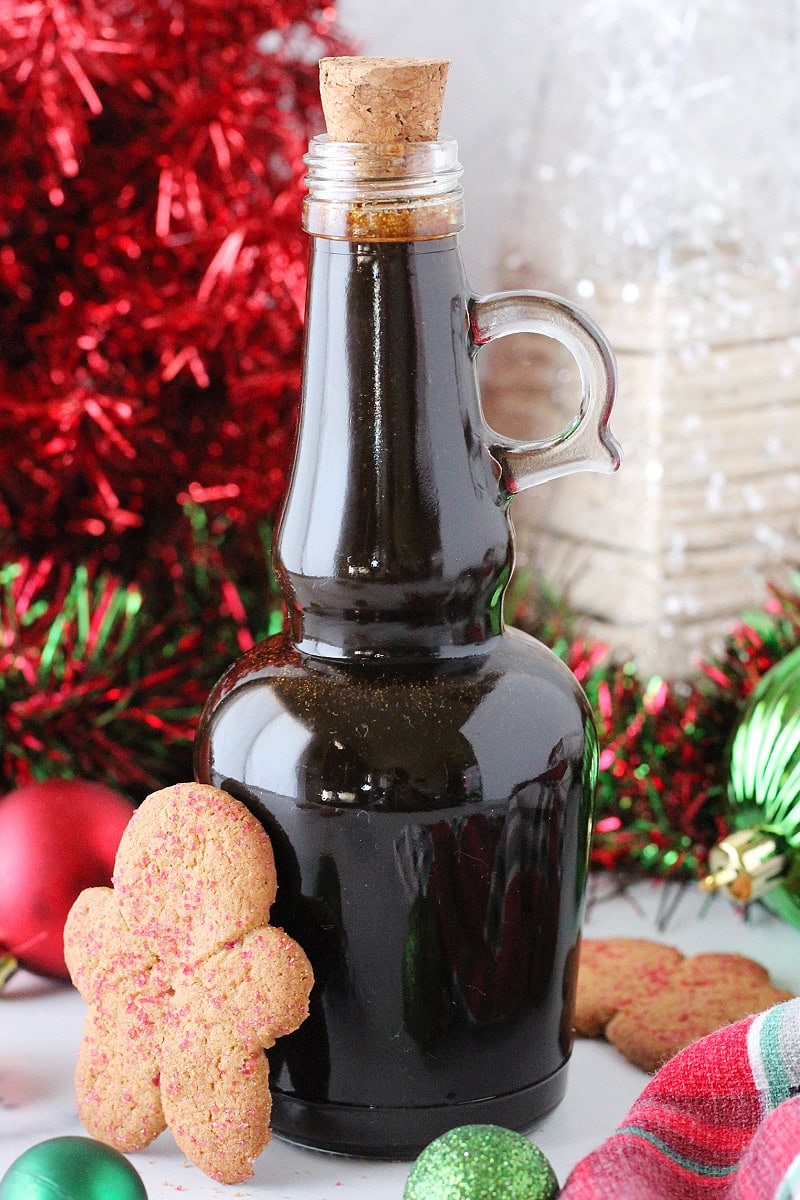 A glass bottle of homemade coffee syrup with a gingerbread man leaning against it.