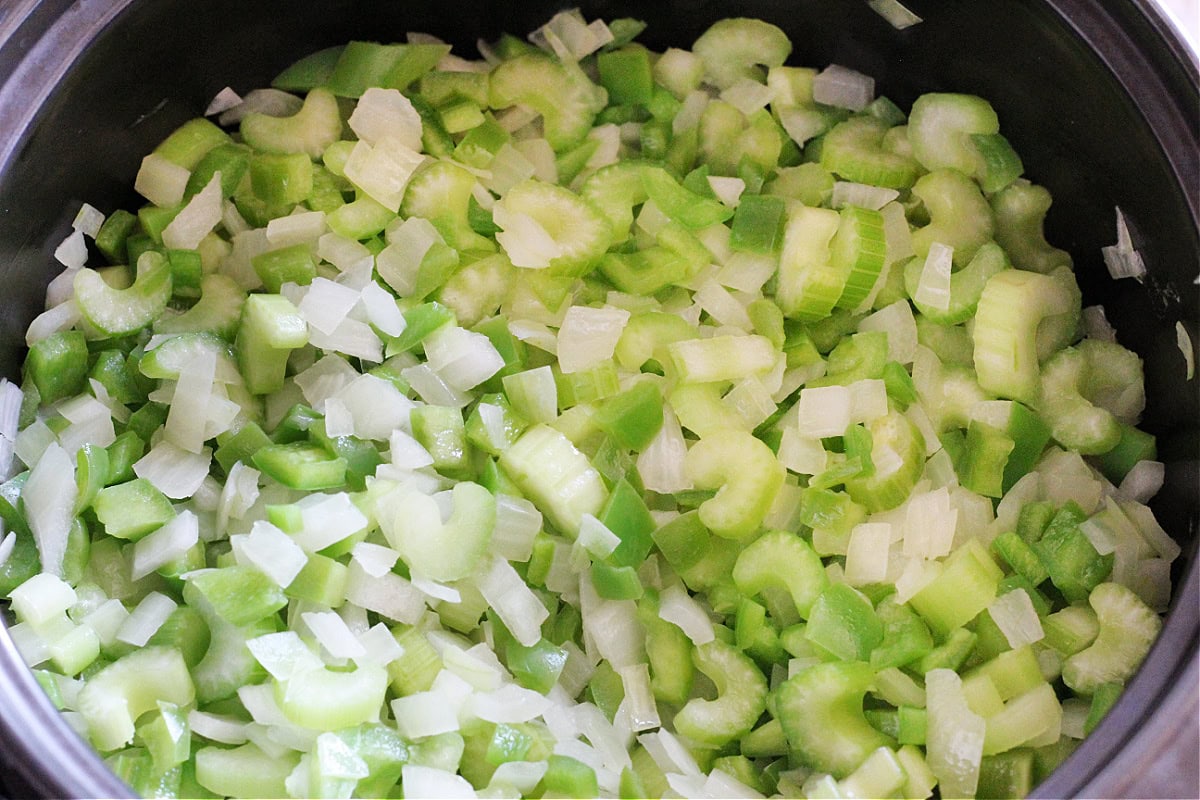 The holy trinity - onion, green pepper and celery in a black soup pot.