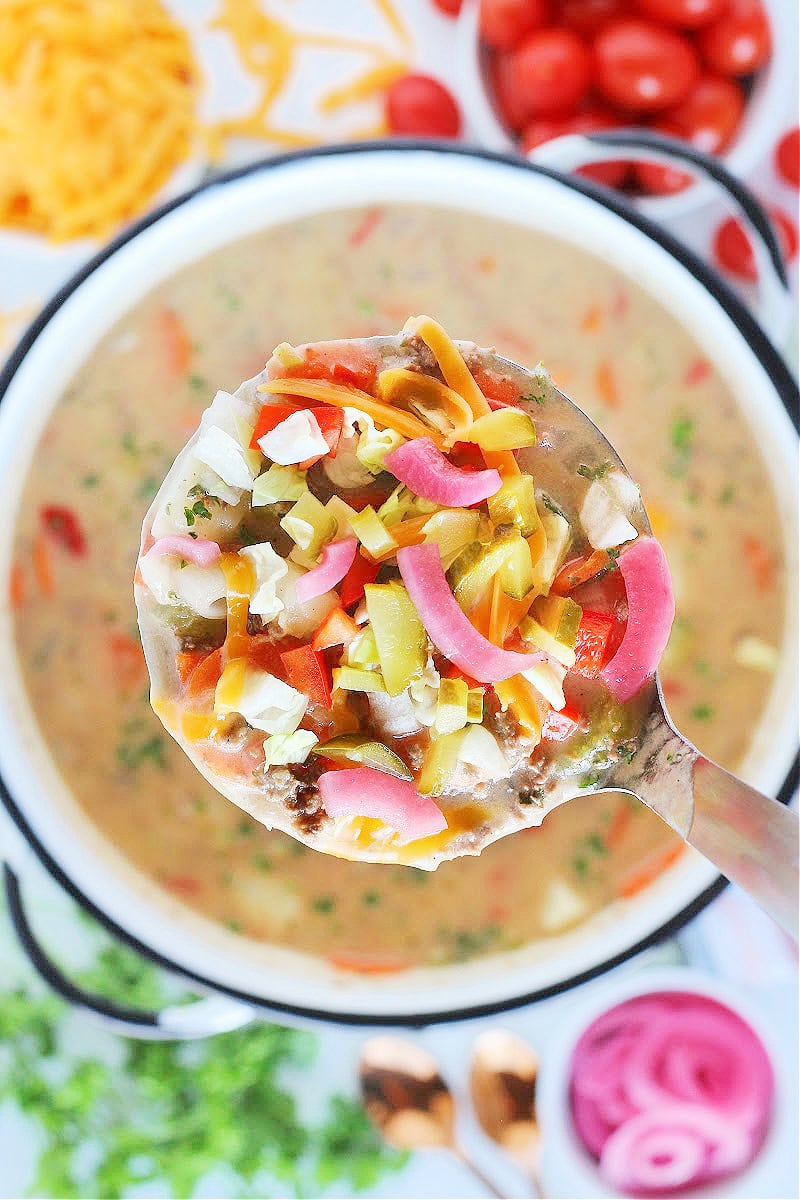 Overhead photo of a ladle of easy cheeseburger soup and pickled onion.