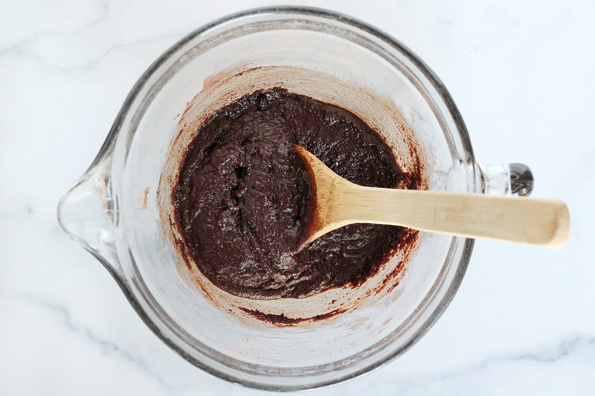 Cocoa powder, eggs and oil mixed together in a glass mixing bowl.