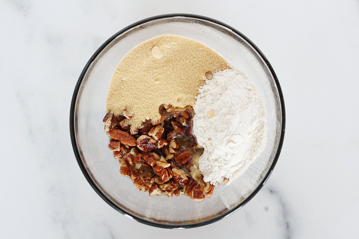 Pecans, flour, golden monk fruit sweetener, and melted butter in a bowl.