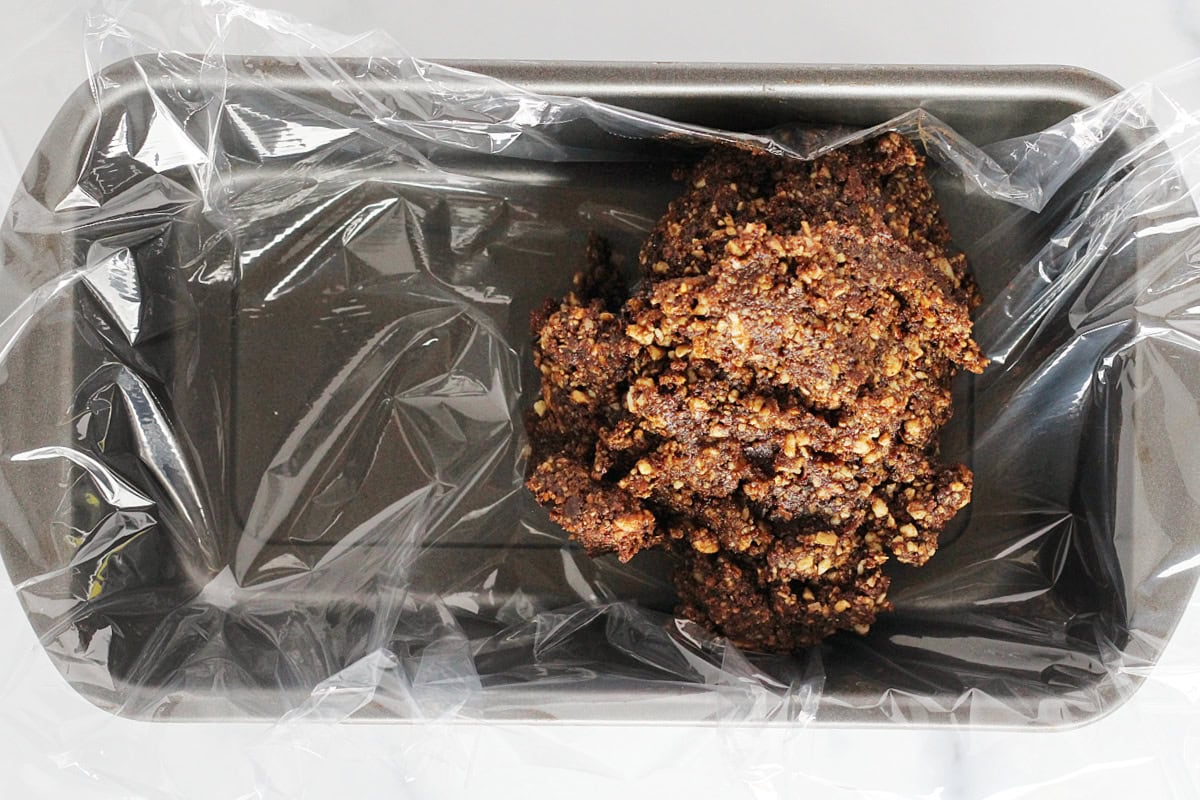 No bake bites batter in a bread pan lined with plastic wrap.