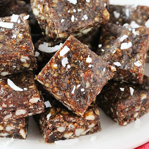 Up close photo of square gingerbread bites on a plate topped with unsweetened coconut shreds.