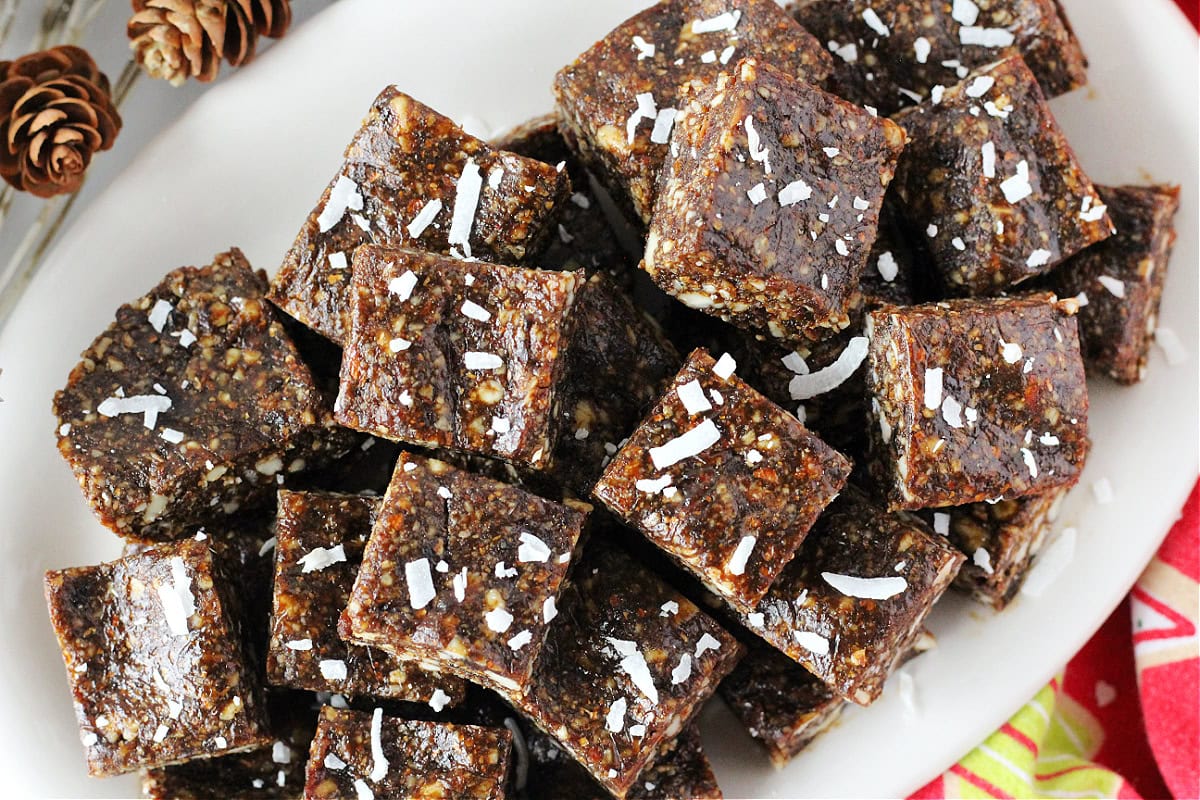 Square gingerbread bites stacked on a plate with shredded coconut on top.