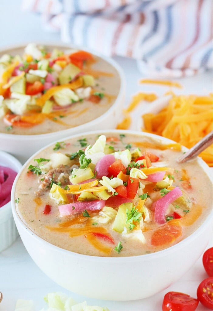 A bowl of healthy cheeseburger soup with a copper spoon in it.