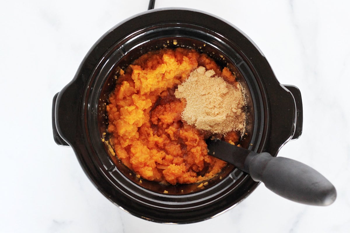 Mashed sweet potatoes in a slow cooker with golden monk fruit sweetener on top.