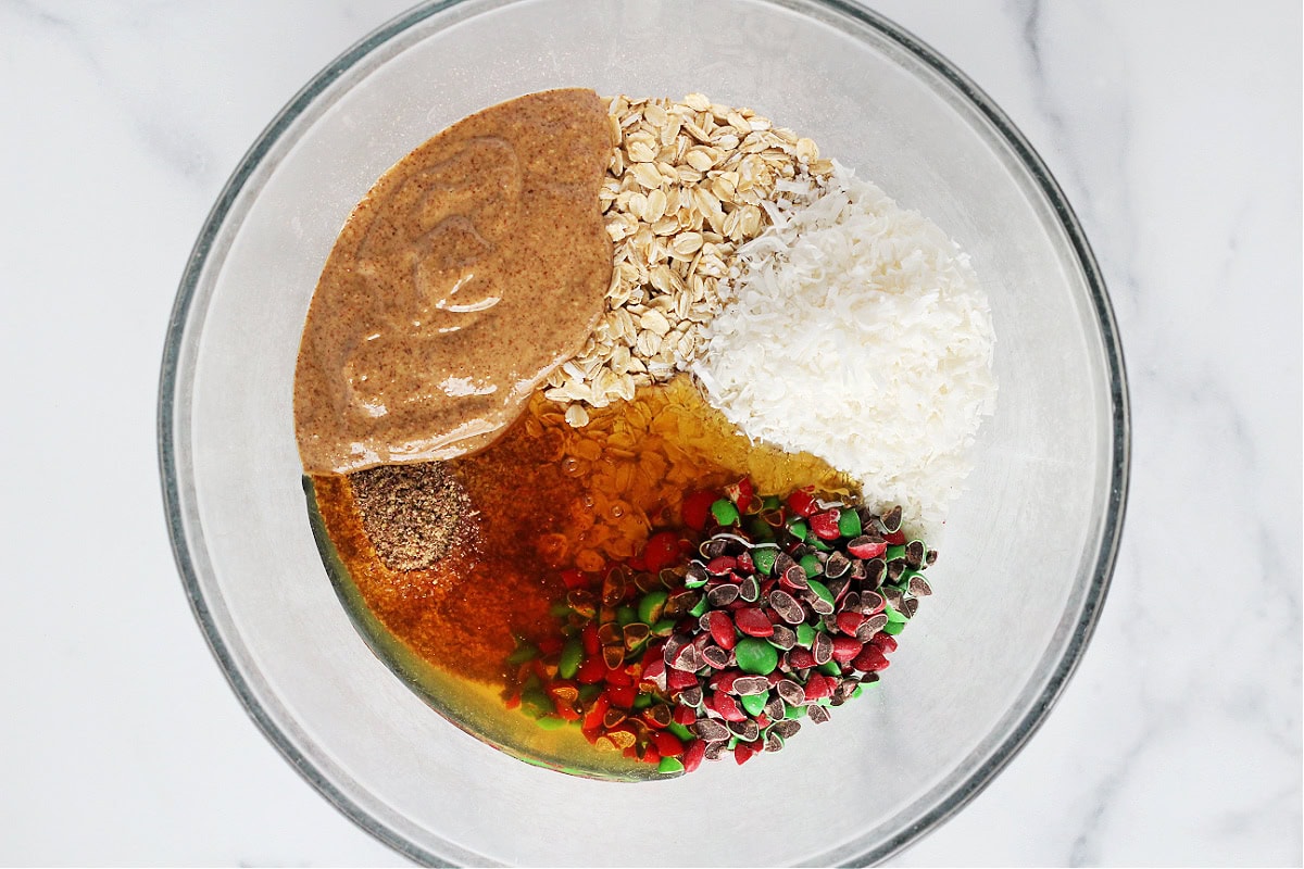 Almond butter, old fashioned oats, honey, shredded coconut, flax seeds and M&Ms in a bowl.