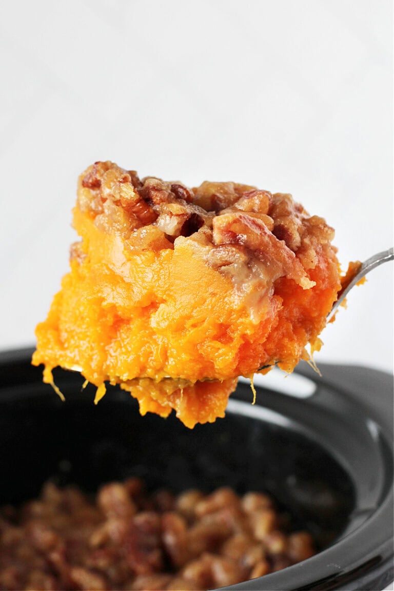 Crockpot sweet potato casserole on a spoon over the slow cooker.