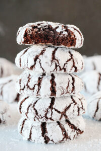 A stack of chocolate crinkle cookies with a bite taken out of the top cookie.