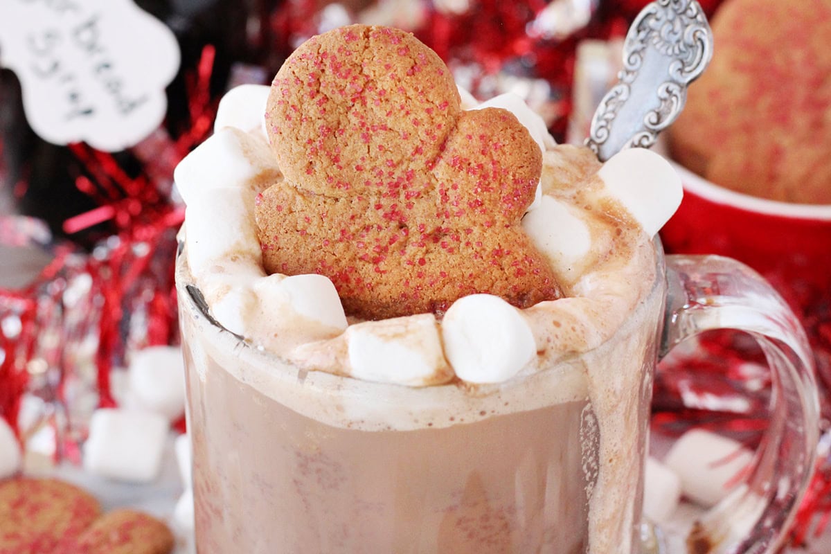 Gingerbread cookie atop a mug of hot cocoa with marshmallows.