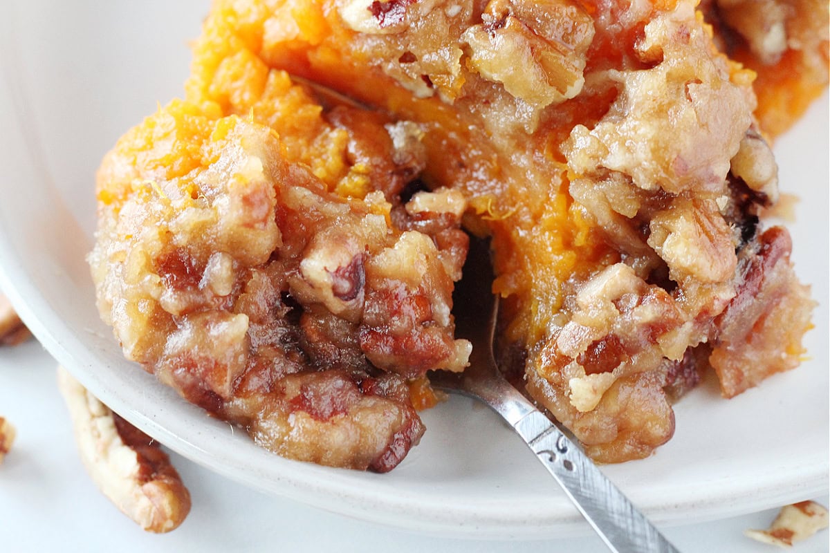 Up close photo of sweet potato casserole on a plate with a spoon.