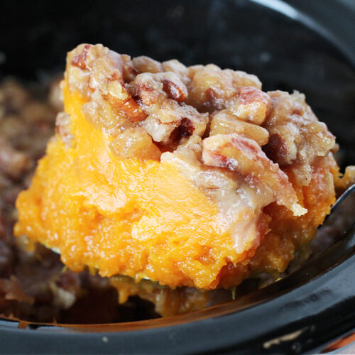 Up close photo of healthy sweet potato casserole on a spoon over the crockpot.