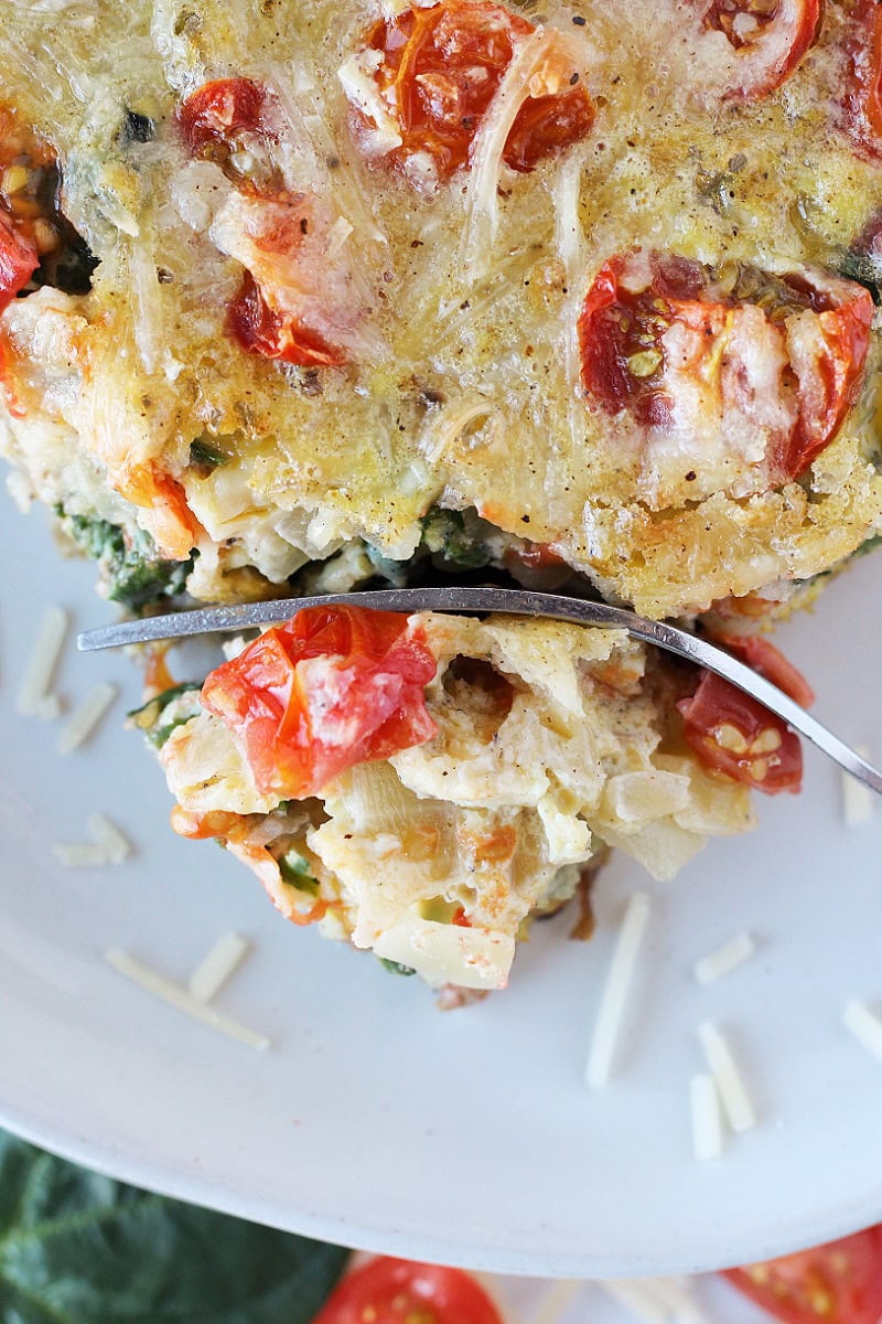 Overhead photo of a fork slicing through a corner of egg casserole with veggies.