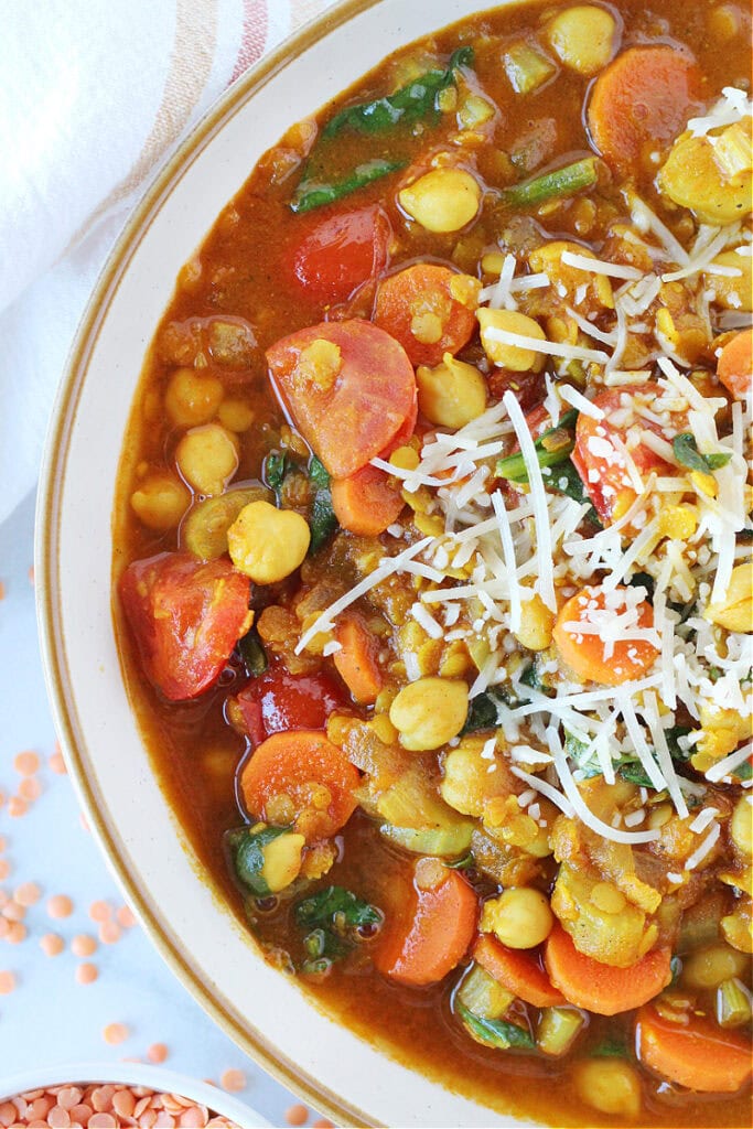 Overhead photo of half a bowl filled with Moroccan chickpea stew topped with Parmesan cheese.