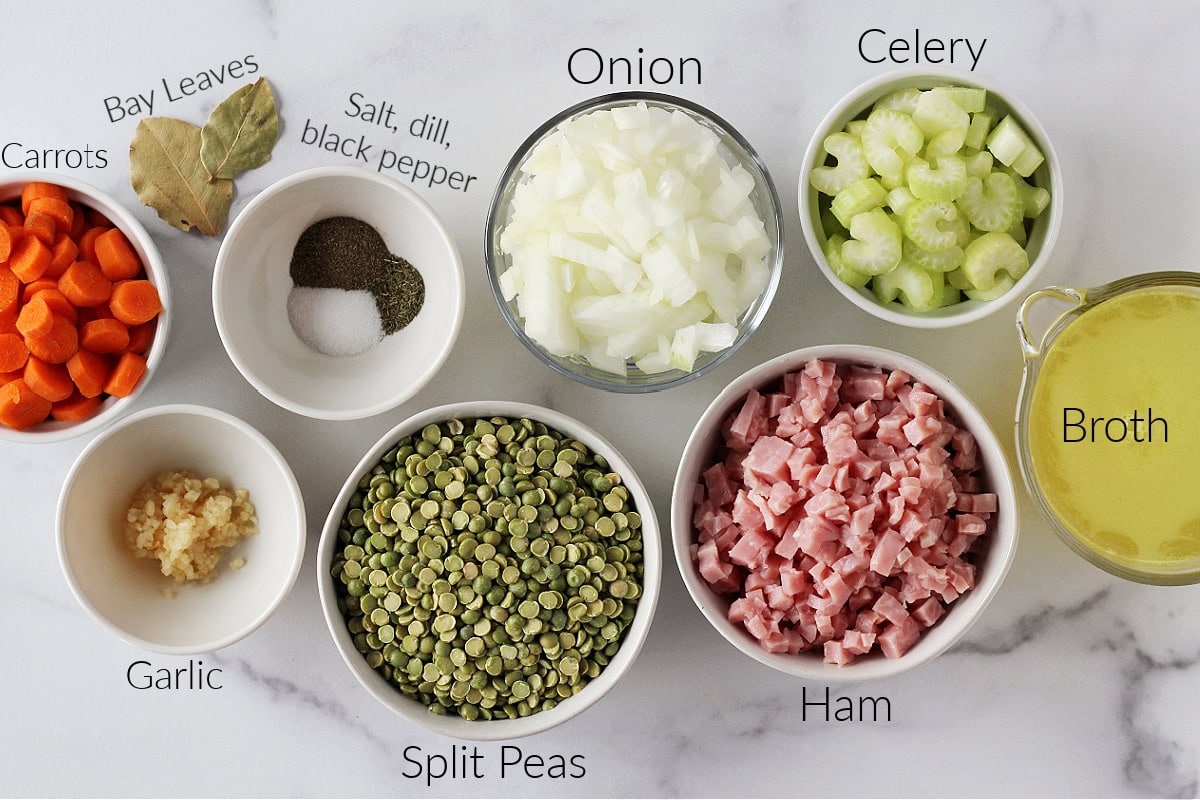 Labeled ingredients in bowls for split pea soup on a white marble countertop.