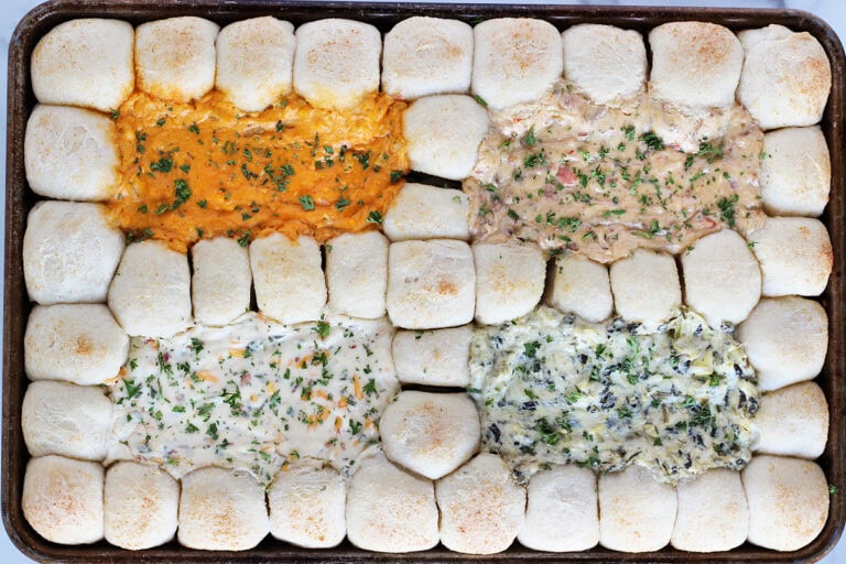 Overhead photo of baked four different dips separated by pizza dough balls dippers.