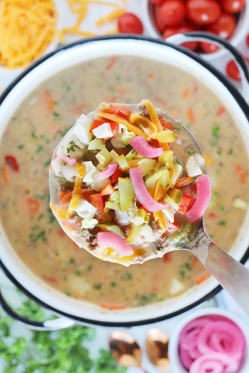 Overhead photo of a ladle of easy cheeseburger soup and pickled onion.