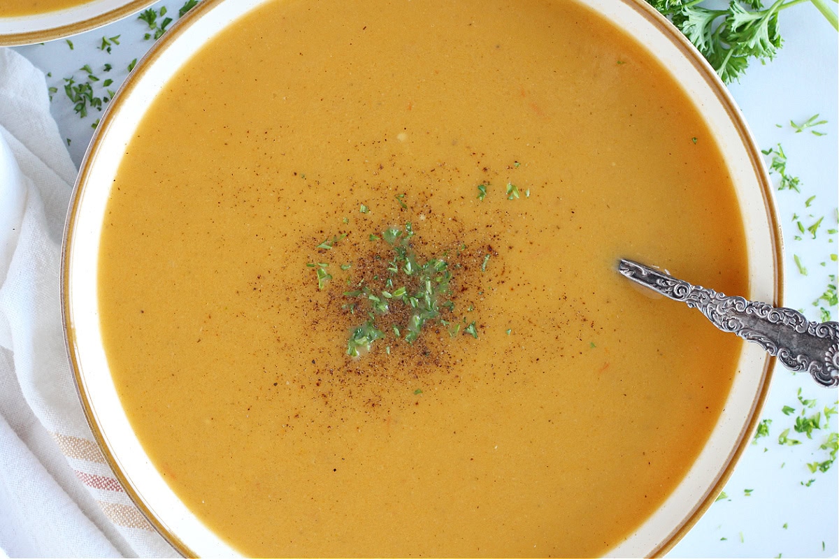 Overhead photo of a bowl of roasted butternut squash soup with a vintage spoon.
