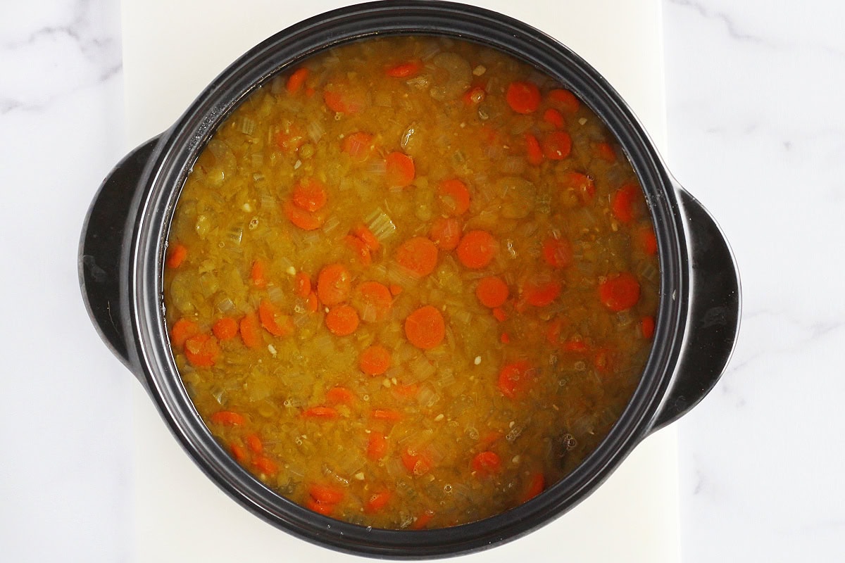 Sliced carrots, celery, softened split peas and broth in a soup pot.