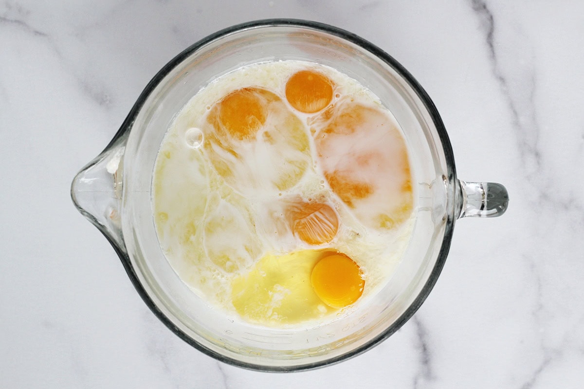 Eggs and coffee creamer in a liquid measuring cup.