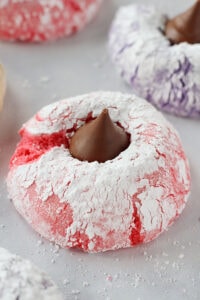 A fluffy pink cookie covered in powdered sugar topped with a Hershey Kiss.