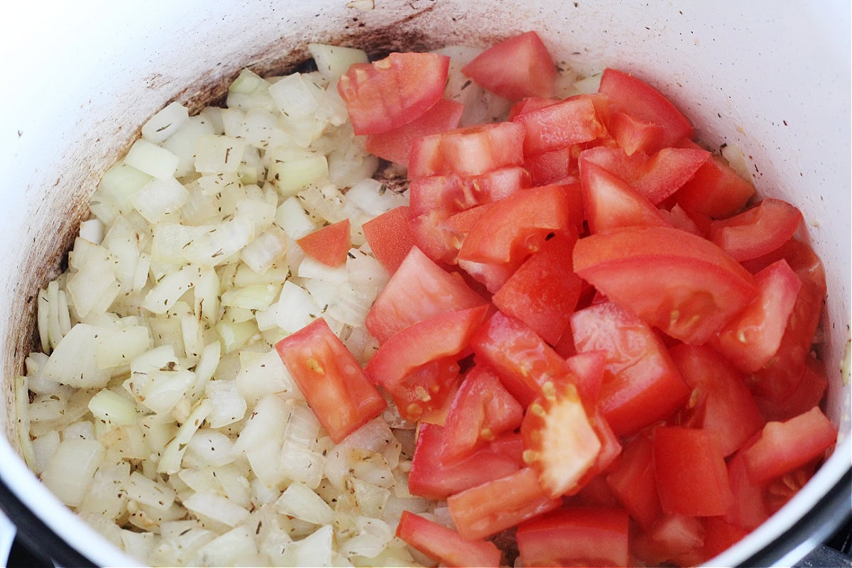 Sauteed onion, garlic and thyme with freshly chopped tomato in a soup pot.