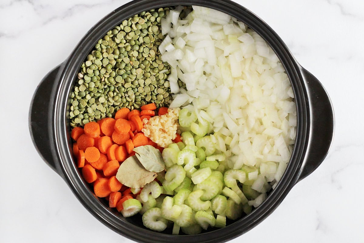 Split peas, diced onion, sliced carrots, celery, bay leaves and minced garlic in a pot.