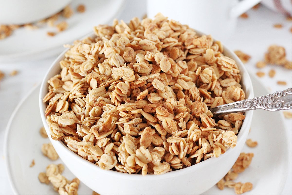 French toast granola in a white bowl with a vintage spoon.