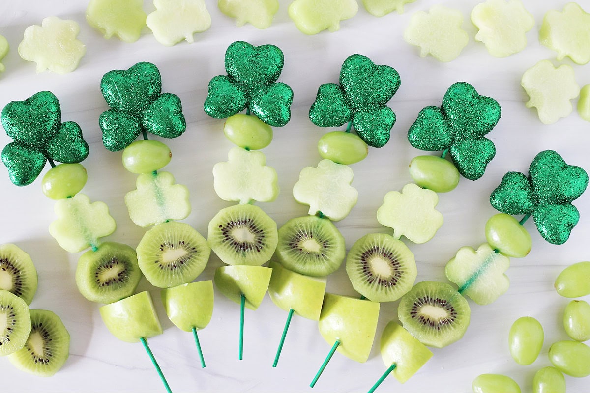 Six green shamrock kabobs threaded with green fruit and melon.