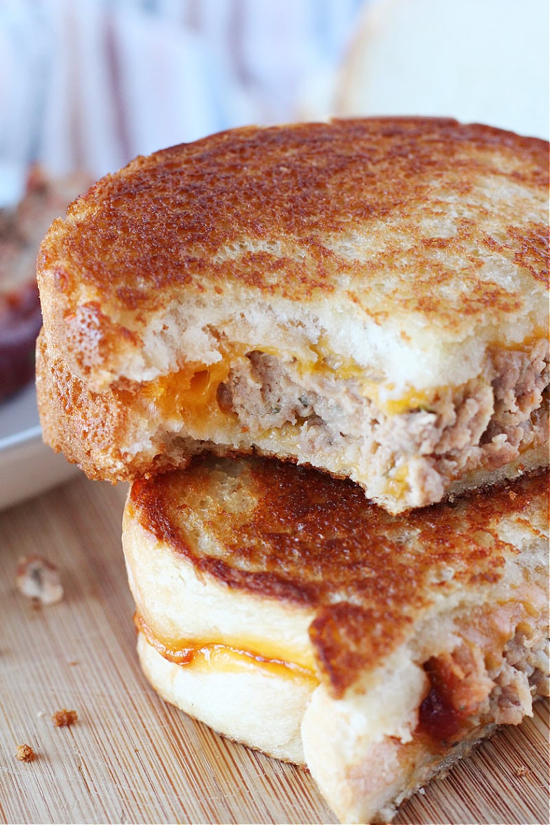 A bite taken out of a grilled cheese with ground beef meatloaf.