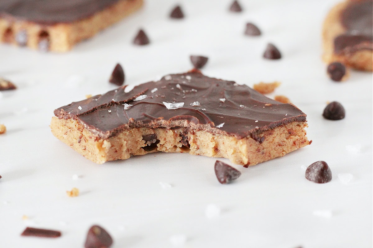 A piece of high protein cookie dough bark with chocolate chips with a bite taken out.