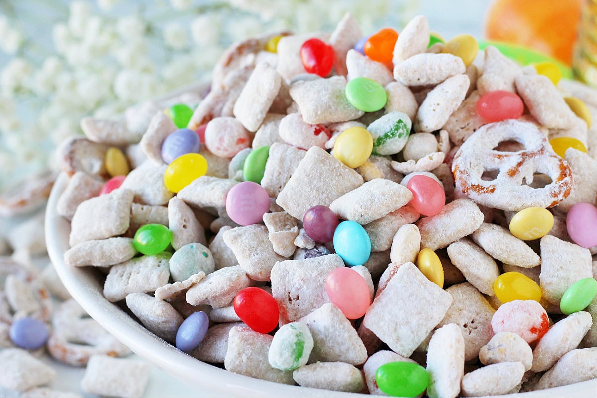 A bowl of powdered sugar coated bunny bait with jelly beans and pastel M&Ms.