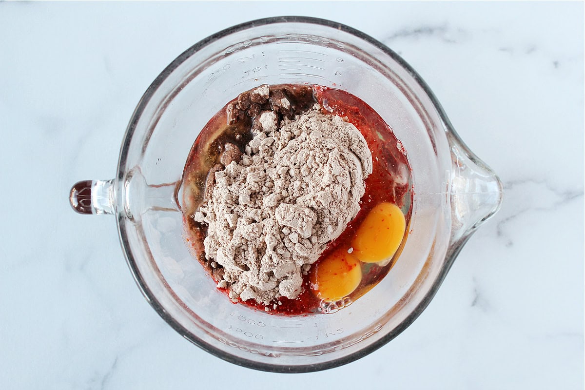Red velvet cake mix, eggs, and oil in a glass mixing bowl.