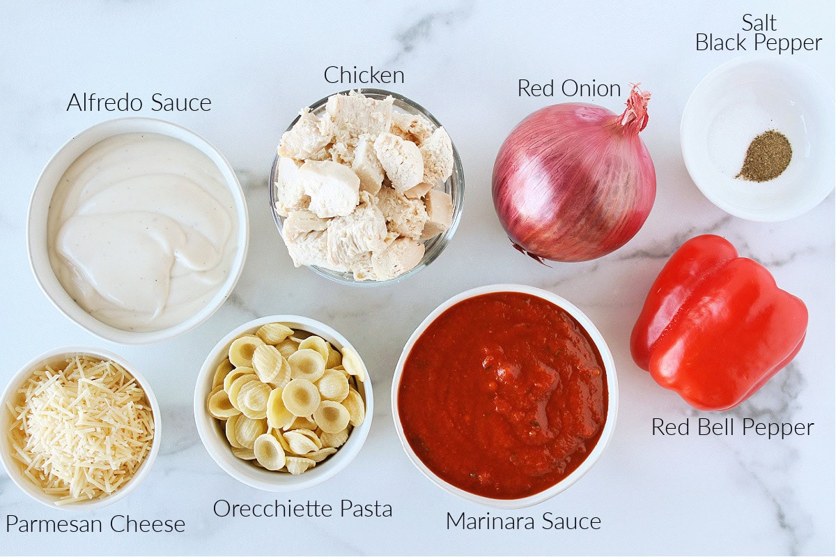Labeled ingredients for chicken orecchiette with rosa sauce on a white marble countertop.