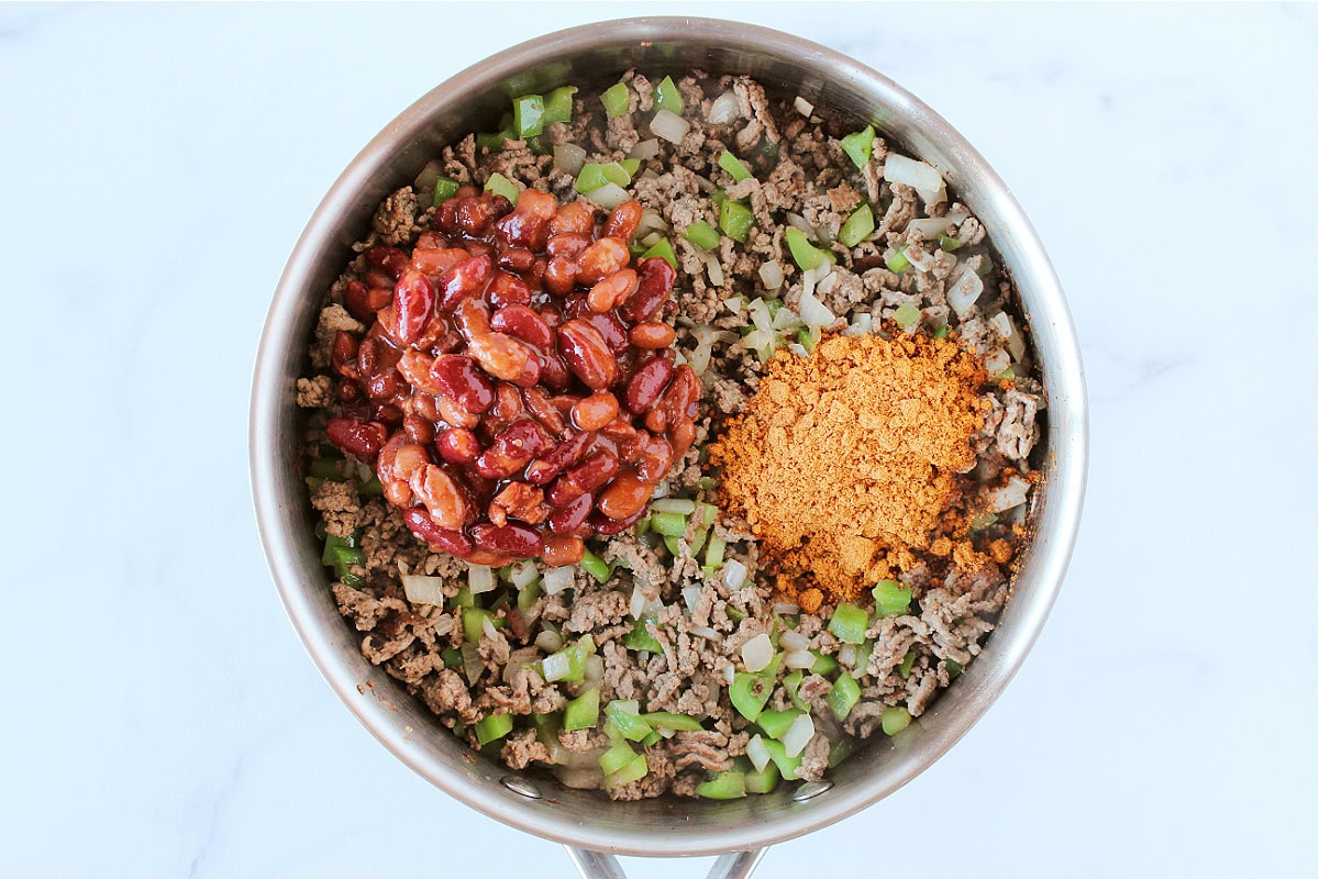 Chili beans and taco seasoning on browned ground beef with veggies.