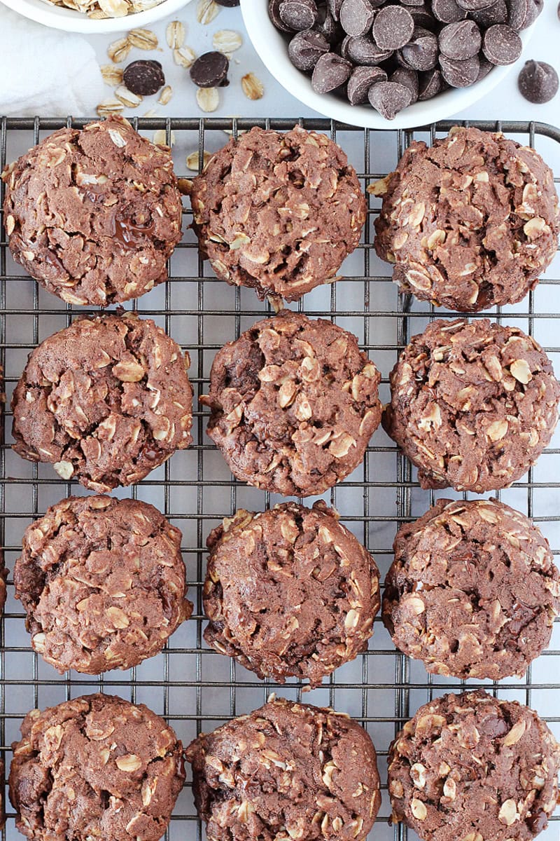 Twelve baked double chocolate oatmeal cookies on a cooling rack.