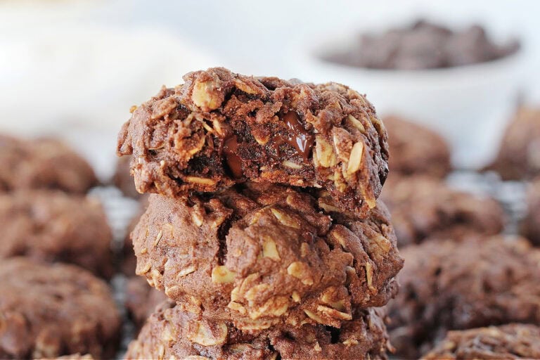 A bite taken out of the top cookie on a stack of chocolate oatmeal cookies.