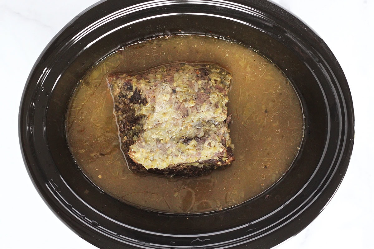 A cooked beef roast in a slow cooker.