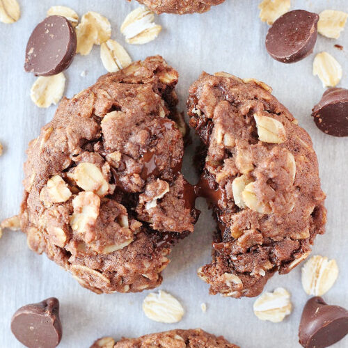 A baked oatmeal cookie split in half with melted chocolate chips.