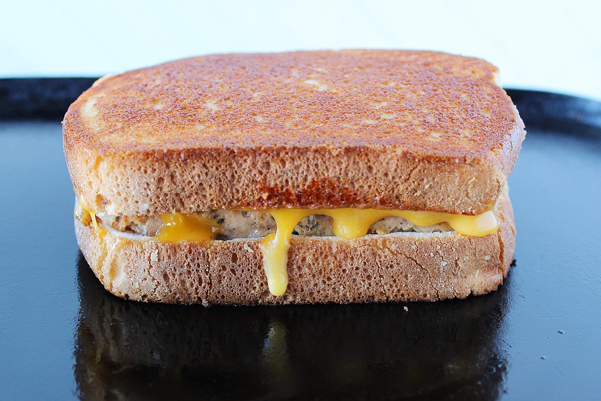Cheddar cheese melted out of a grilled meatloaf sandwich.