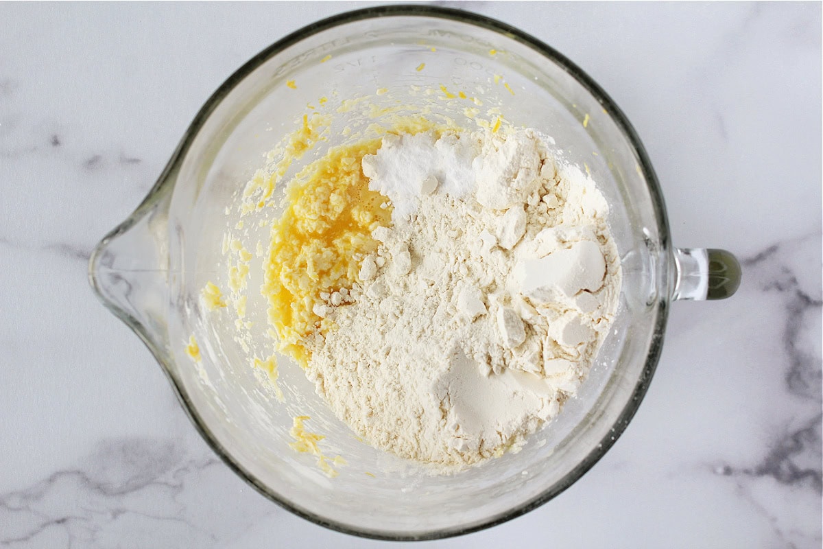 Flour and baking soda added to wet ingredients in a mixing bowl.